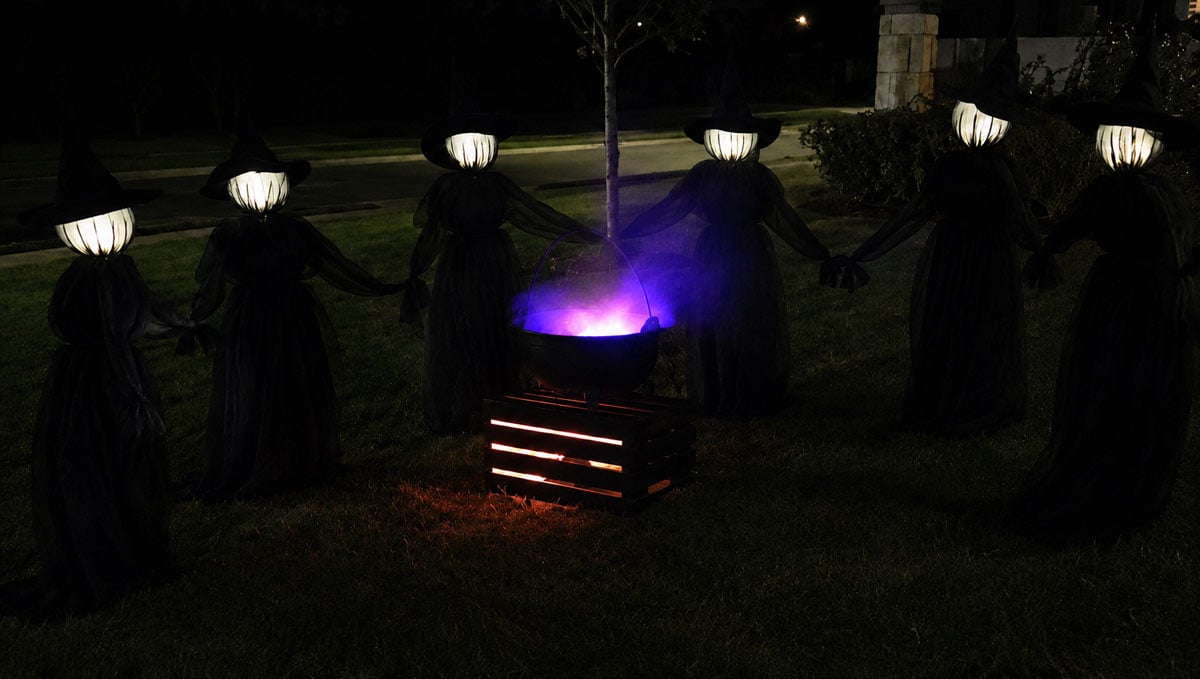 DIY bubbling cauldron with purple mist and glowing witches in an outdoor Halloween display