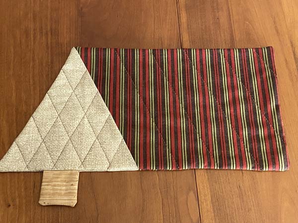 Reversible quilted Christmas tree mug rug displayed on a table