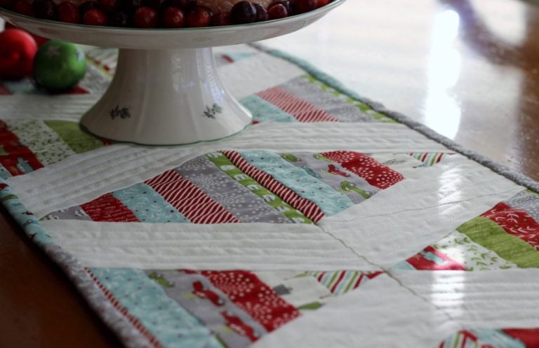 Scrappy quilted Christmas table runner made from mixed holiday prints
