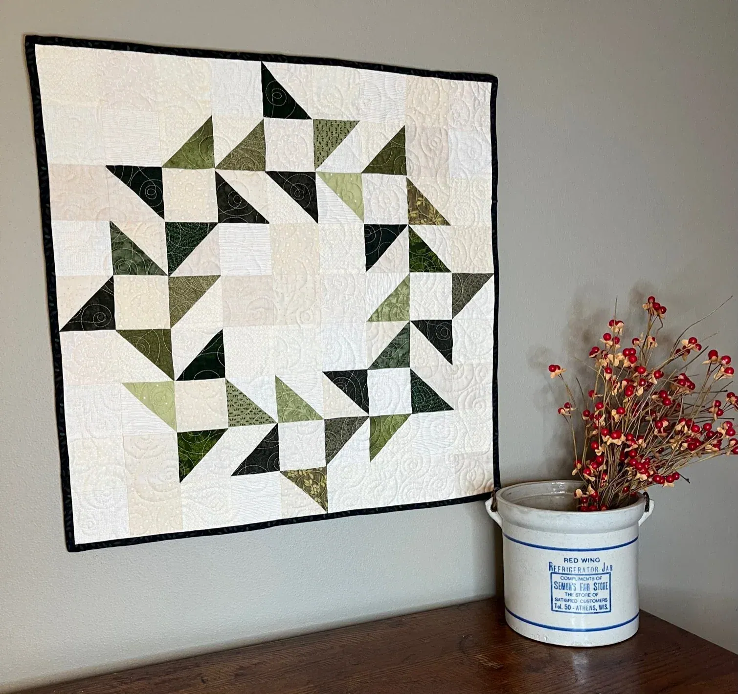 Evergreen wreath quilt displayed with Christmas greenery and red berries