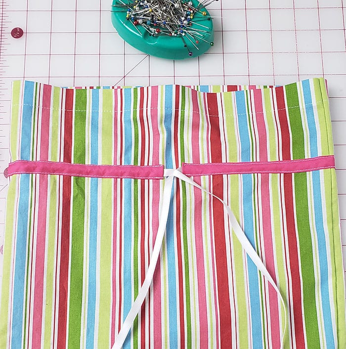 White ribbon ends emerging from the pink casing and tied together