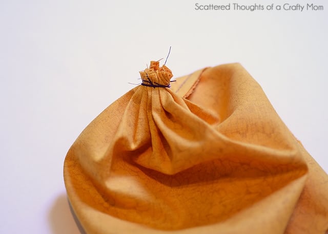 Gathering the bottom of a fabric pumpkin