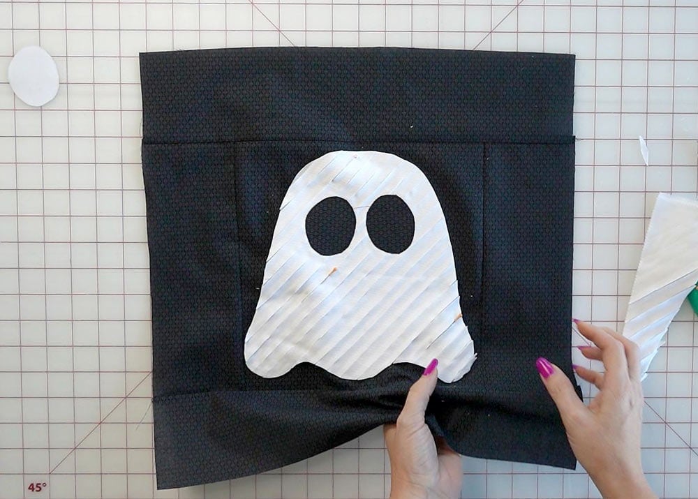 Pinning the textured ghost appliqué onto the black pillow front