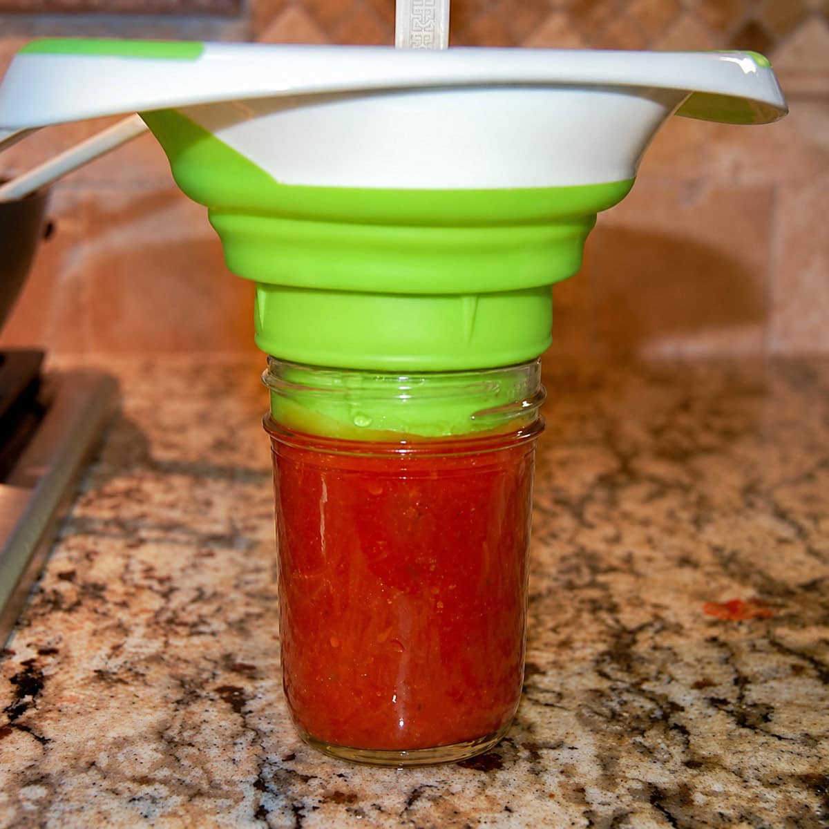 Ladling hot pizza sauce into canning jars