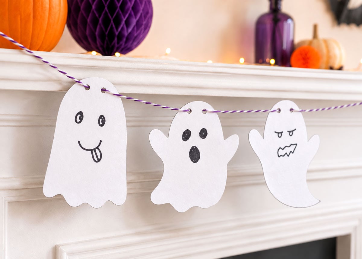 Finished printable Halloween ghost garland hanging across a decorated mantel