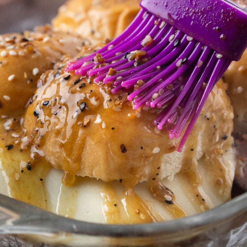 Brushing seasoned butter over roast beef sliders