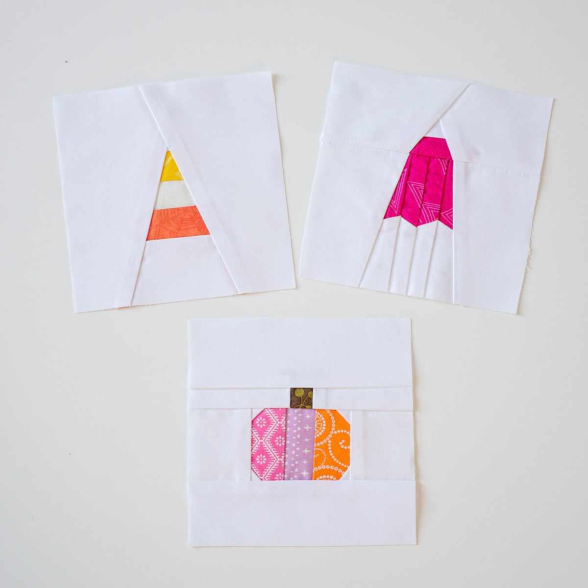 Mini Halloween quilt blocks featuring a pumpkin, candy corn, and ghost sewn from colorful scraps