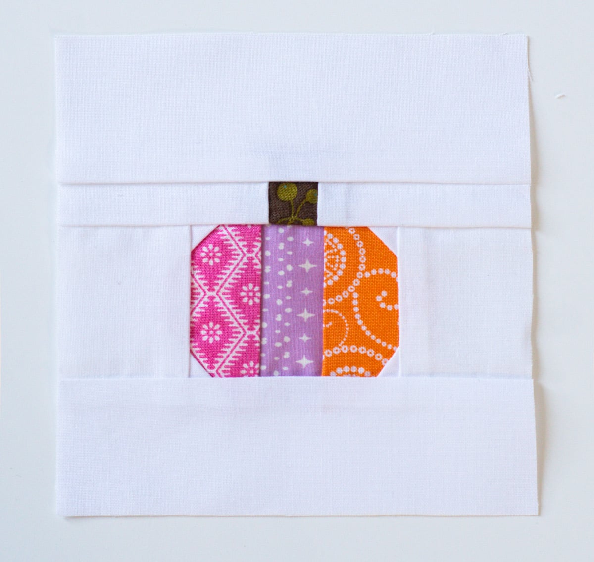 Completed mini pumpkin quilt block with pink lavender and orange patchwork